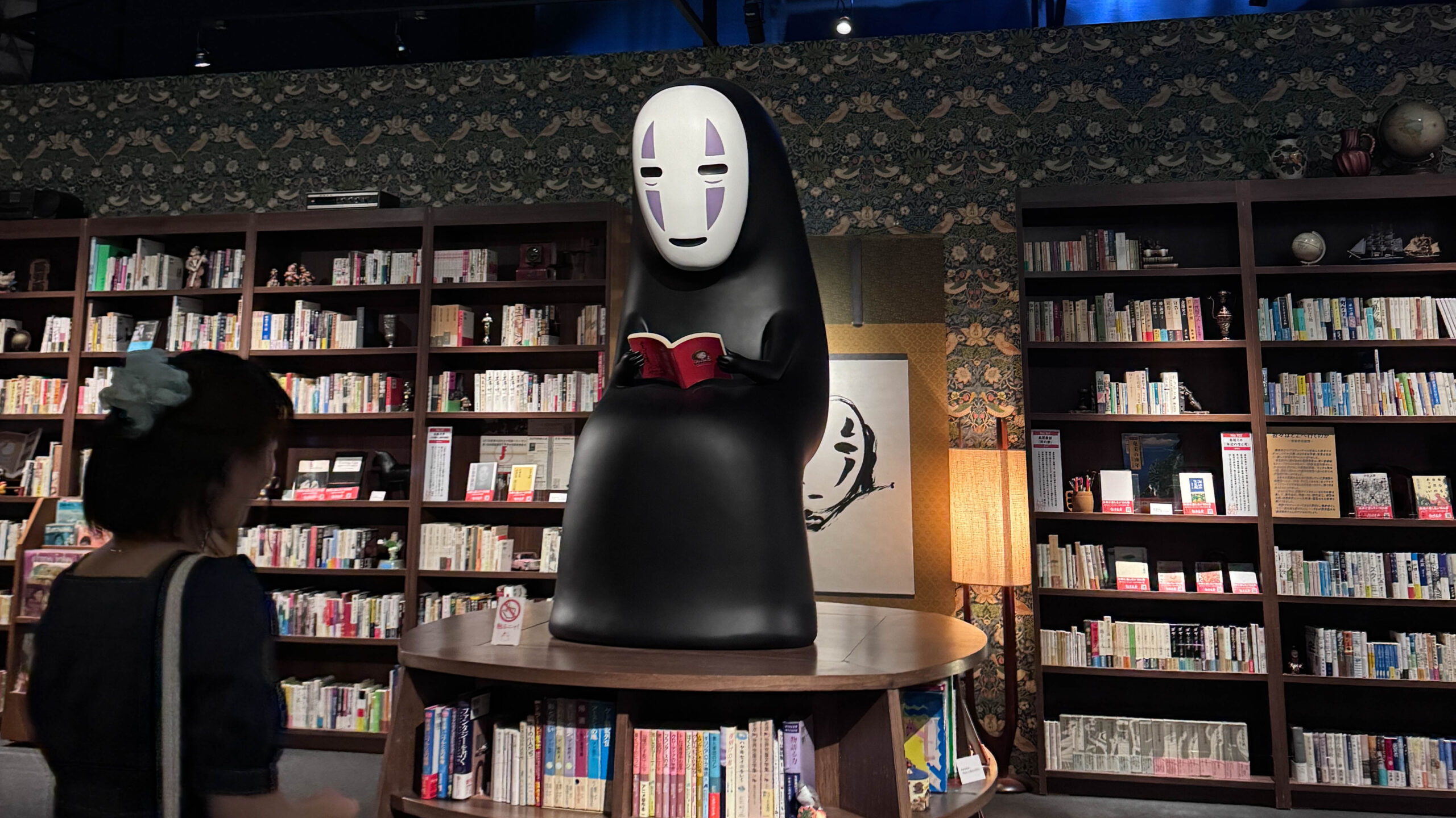 รูปปั้น No-Face ตัวละครดังจาก Spirited Away กำลังอ่านหนังสือในโซนจัดแสดง Studio Ghibli